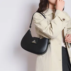 Detail of black crescent hobo bag with pebble leather texture and silver triangle buckle