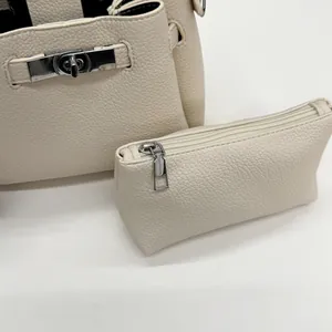 Detail of creamy white litchi grain leather bucket bag with silver metal twist lock clasp