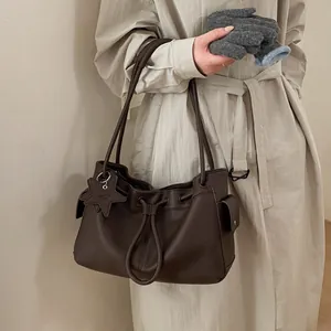 Detail of dark brown leather tote bag with star charm and drawstring detail on model