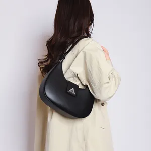 Detail of black crescent shoulder bag with silver triangular logo on leather texture