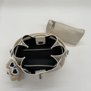 Internal view of cream bucket bag with small pouch and cute sheep keychain accessory