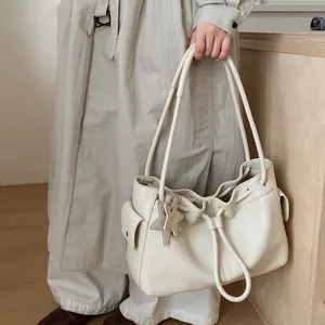 Detail of off-white leather tote bag featuring drawstring closure and star-shaped charm