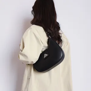 Minimalist black crescent leather shoulder bag shown on model with silver buckle detail