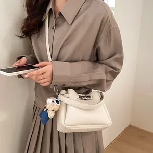 Detailed view of cream leather bucket bag with silver twist lock and bear charm