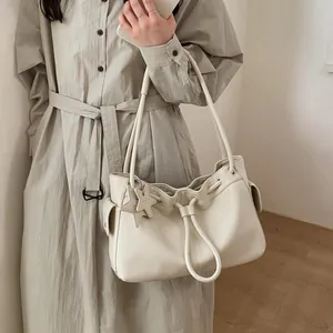 Close-up of cream leather tote bag with drawstring closure and star-shaped charm detail