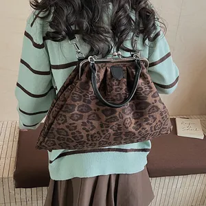Detailed view of leopard print handbag with vintage metal frame and leather handles