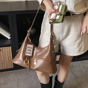 Detailed close-up of a brown vintage hobo bag worn by a model in a cozy interior setting