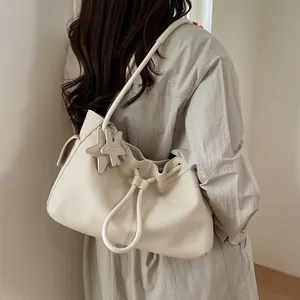 Detail of cream white lychee leather shoulder bag with drawstring and star charm pendant