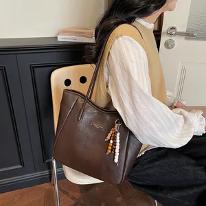 Detail of vintage brown tote bag with leather texture and wooden bead charm accessory