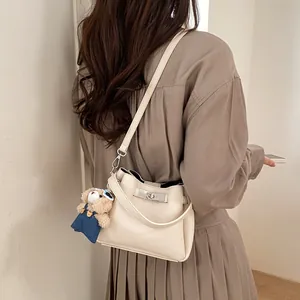 Detail of cream leather bucket bag featuring a gold twist lock and blue bear charm