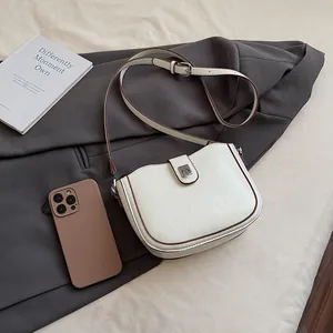 Detail of white lychee leather saddle bag with silver buckle and dark brown edges