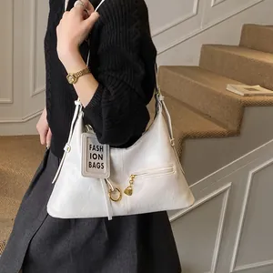 Close-up of white tote shoulder bag with gold hardware and a fashion brand tag