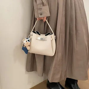 Close-up of off-white lychee grain leather bucket bag with silver twist lock and bear charm