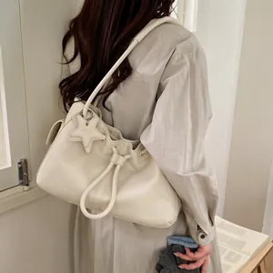 Detail of cream white leather tote bag featuring drawstring closure and star charm