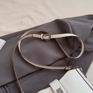 Close-up of beige saddle bag showing crackle texture and silver square buckle detail