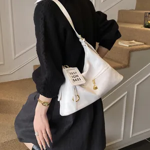 Detail of white leather shoulder bag with FASHION BAGS tag and gold zipper accents