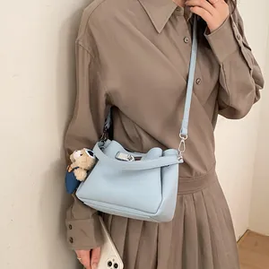 Light blue faux leather bucket bag with silver clasp and plush bear charm decoration