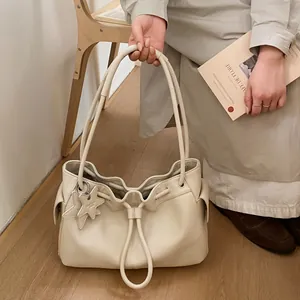 Detail of creamy white drawstring tote bag with lychee texture leather and star charm