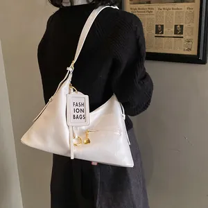 Detail of white Hobo shoulder bag with gold hardware and fashion tag ornament