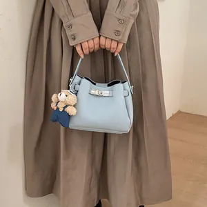 Light blue lychee pattern bucket bag featuring a silver metal clasp and plush bear charm