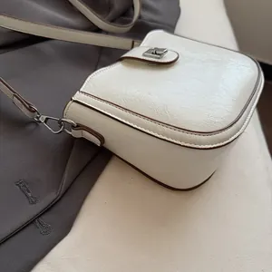 Detail of cream saddle bag featuring crackled oil wax texture and brown edge paint