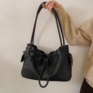 Close-up of black litchi grain leather tote bag with drawstring and star charm