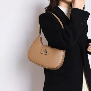 Detail of khaki crescent shoulder bag with silver triangular buckle on model wearing black coat