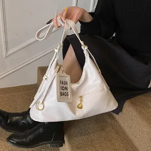 Close-up of white leather hobo bag showing golden hardware and a transparent card holder