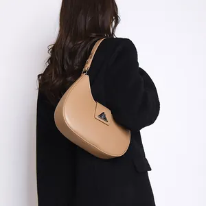 Detailed view of the crescent shoulder bag with triangular metal logo and adjustable strap