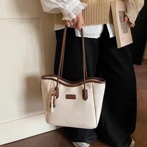 Detail of cream leather tote bag with brown trim and ethnic beaded pendant charm