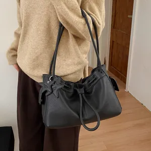 Detail of black pebbled leather tote bag featuring a star pendant and drawstring closure