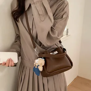 Brown litchi grain leather bucket bag featuring a silver twist lock and bear charm