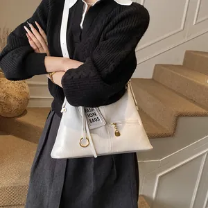 Detail of white leather underarm bag with metal ring and fashion bags hangtag detail