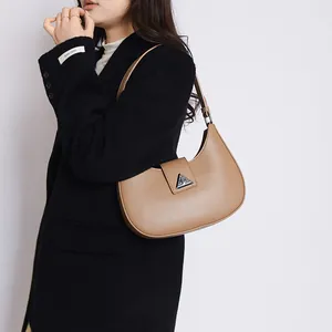 Detail of hobo crescent bag in camel leather with silver triangular metal buckle on black coat