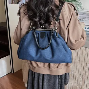 Detail of blue denim cloud bag with metal clasp and black leather straps as a backpack