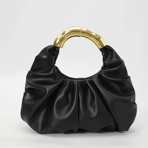 Détail du sac dumpling noir plissé montrant la texture cuir et la poignée dorée bambou