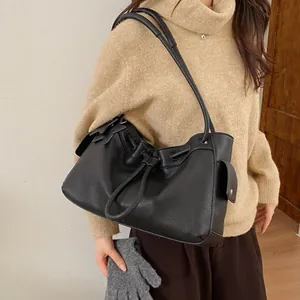 Detail of black pebbled leather tote bag with drawstring closure and side flap pocket