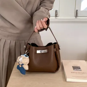 Detail of dark brown pebble leather bucket bag with silver twist lock and bear charm