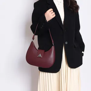 Detail of burgundy crescent shoulder bag with silver logo on a fashion model