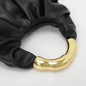 Détail d'un élégant sac à main en cuir plissé noir avec poignée en métal doré ondulé