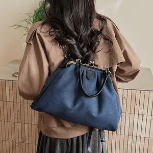 Detail view of denim blue pleated frame bag with gold hardware and leather strap