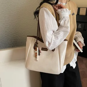 Detail of retro cream tote bag with brown trim and vintage wooden bead pendant