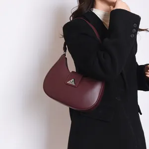Detail of dark wine red crescent shoulder bag worn with a black wool coat for women