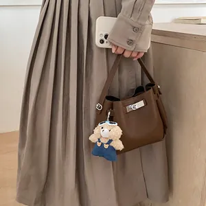 Detail view of dark brown pebbled leather bucket bag with a cute plush bear charm