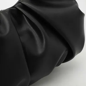 Gros plan sur la texture froncée en similicuir noir d'une pochette de soirée