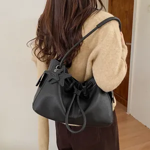 Close-up of black litchi texture leather tote bag featuring star-shaped pendant detail