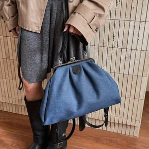 Detail of blue denim doctor bag with metal clasp, vintage pleats and leather handle
