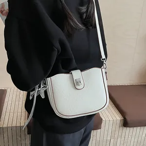 Detail of off-white saddle bag with silver star charm and adjustable crossbody strap