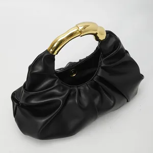 Détail du sac plissé noir avec une poignée métallique dorée au design artistique chic