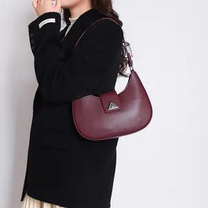 Close-up of matte burgundy leather hobo bag featuring a distinctive triangle metal clasp